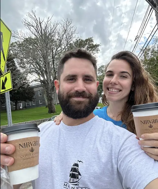 Vini e a esposa com copos de café na rua