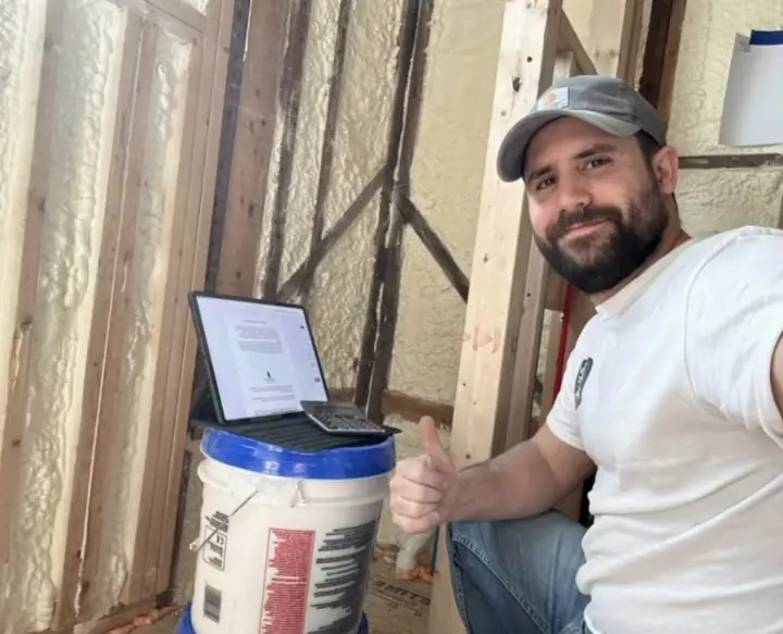 Vini na obra com o iPad e a calculadora em cima de um balde