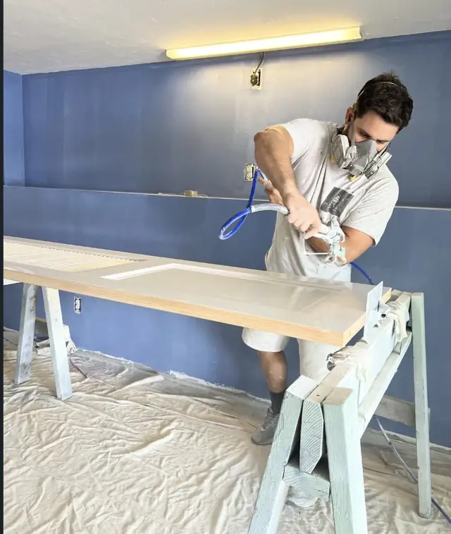 Vini pintando uma porta com pistola, de máscara